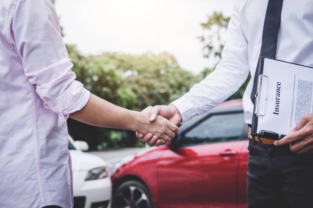 Drivers exchanging insurance papers after minor car accident.